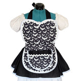 A black and white apron with a repeating bat pattern, styled on a teal dress form with white puffed sleeves against a white background.